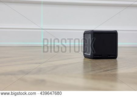 Cross Line Laser Level On Floor In Front Of White Wall