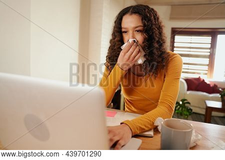 Multi-cultural Female Typing From Home On Laptop Whilst Blowing Her Nose. Sickness Whilst Working Fr