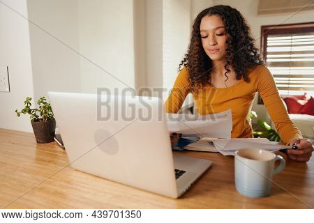 Multi-cultural Female Paying Bills From Home. Young Professional Remote Working With Laptop In Moder