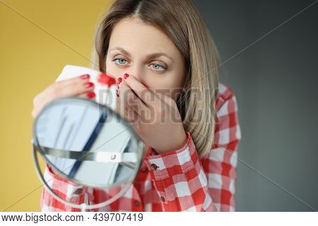 Young Woman Looks In Mirror And Bleeds From Nose. Nosebleeds Concept