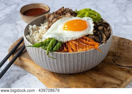 Bibimbap Korean Food, Rice Bowl With Mushroom, Carrot, Ground Beef And Egg. On A Wooden Board And Li