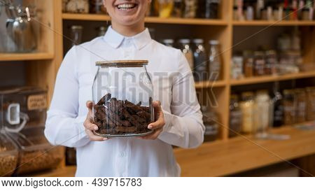 A Woman Holds Croutons In A Glass Jar. Eco Shop Without Plastic Waste.