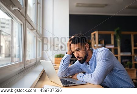 Depressed Young African-american Teacher Using Laptop Indoors In Staffroom.