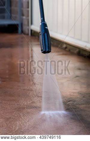 Cleaning Dirty Backyard Paving Tiles With Pressure Washer Cleaner.