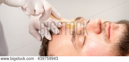 Beautician Applying Wax Paste Between Eyebrows During The Procedure Of Waxing In The Beauty Salon