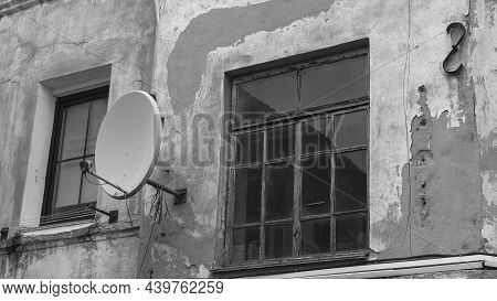 A Fragment Of An Old Building With A Round Satellite Dish On The Wall. Windos On Rear Facade Of Hous