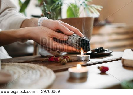 Woman Hands Burning White Sage, Palo Santo Before Ritual On The Table With Candles And Green Plants.