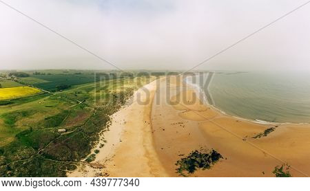 Embleton Bay and Burn with sandy beach with the ruins of Dunstanburgh Castle