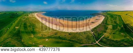 Embleton Bay and Burn with sandy beach with the ruins of Dunstanburgh Castle