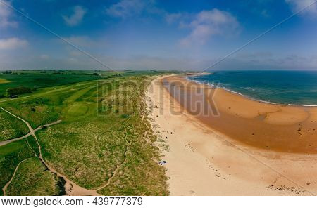 Embleton Bay and Burn with sandy beach with the ruins of Dunstanburgh Castle