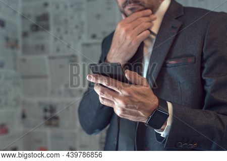 Businessman Using Mobile Phone In Fake News Infodemic Concept With Tabloid Newspaper Pages In Backgr