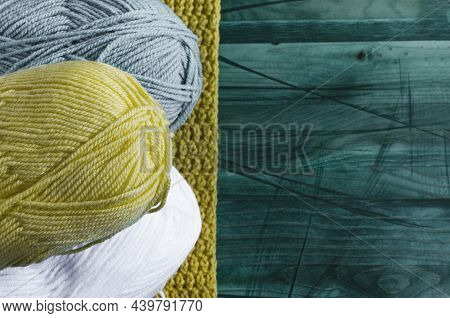 Balls Of Colored Yarn On A Green Wooden Background Knitting Concept. Colored Yarn Of A Light Shade O