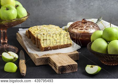 Sliced Apple And Coconut Oaf Cake On Wooden Cutting Board On Dark Background