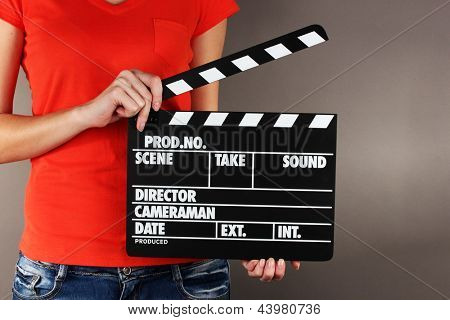 Consiglio di batacchio produzione film in mani su sfondo grigio