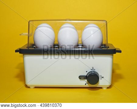 Electric Egg Cooker Or Egg Boiler With Eggs On Yellow Background. Egg Cooker With Cooking Time Contr