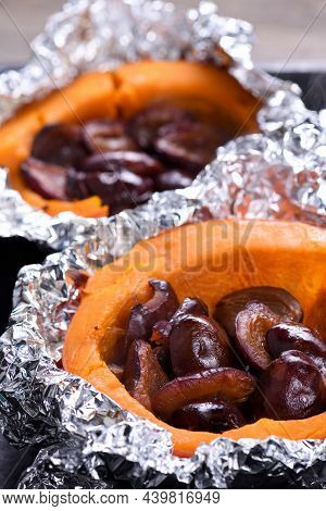 Hokkaido Pumpkin Halves Baked In Foil Stuffed With Plums On A Baking Sheet. Vegetarian Food. The Ket