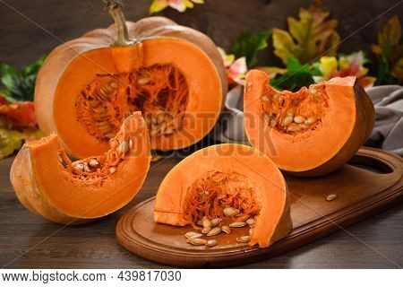 Whole Fresh Orange Big Pumpkin And Slice Of Pumpkin On Wooden Board, Closeup. Organic Vegetable Prod