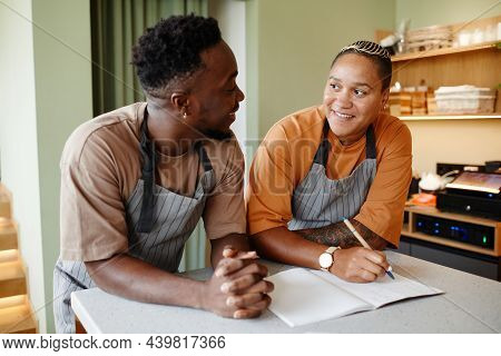 Portrait Of Young African American Man And Woman Starting Workday In Modern Cafe With Creating New M