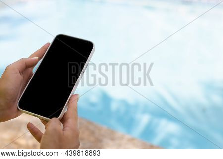 Female Hand Holding Smartphone Near Swimming Pool. Closeup, Mock Up.