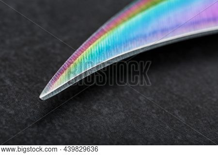 The Curved Sharp Blade Of The Kerambit Dagger Is A Gradient Rainbow Color On A Dark Background.