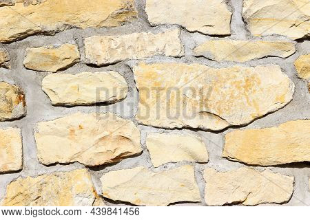 Wall Made Of Natural Rocks Of Different Sizes And Shapes With Wide Gaps Filled With Cement As A Back