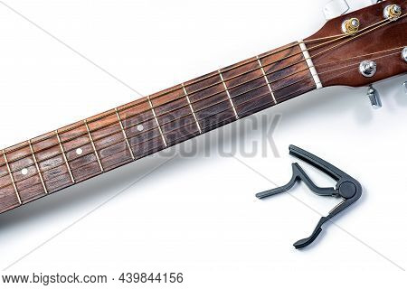 Classic Acoustic Guitar And A Capo On A White Background, Close-up.