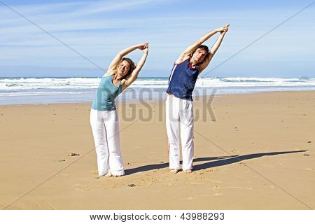 Coppia facendo excersises yoga in spiaggia