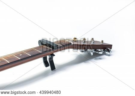 Classic Acoustic Guitar And A Capo On Second Fret Strings, White Background, Close-up.