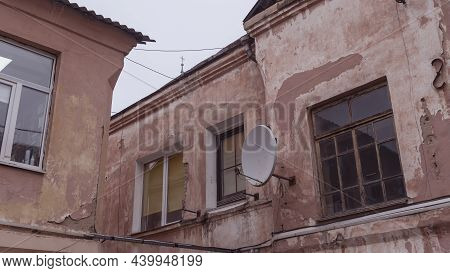 A Fragment Of An Old Building With A Round Satellite Dish On The Wall. Windos On Rear Facade Of Hous
