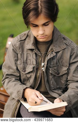 Handsome Teenager Painting Something In His Notepad Outdood During The Break. Talanted Young Boy
