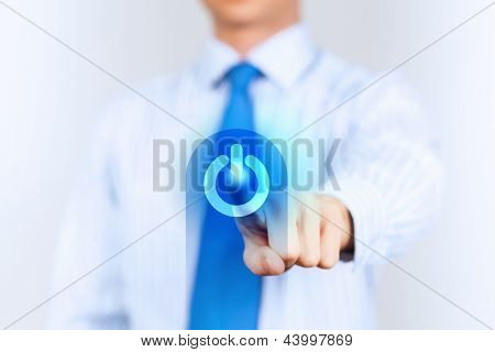 Young man in a light shirt and blue tie press the power button. Shallow depth of field.