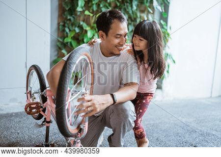 Father And Daughter Repairing Childs Bicycle Whee