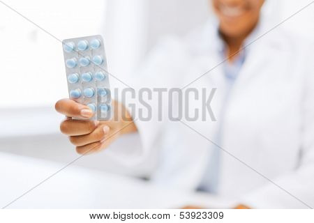 health and medicine concept - female doctor hand giving pack of pills