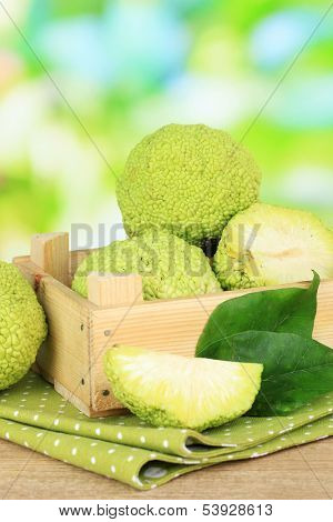 Osage Orange fruits (Maclura pomifera) in crate, on wooden table, on nature background