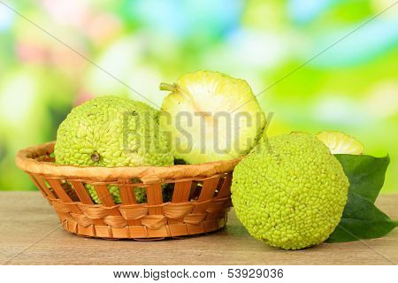 Osage Orange fruits (Maclura pomifera) in basket, on wooden table, on nature background