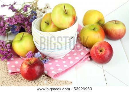 Juicy apples on plate on white wooden table