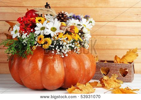 Beautiful autumn composition in pumpkin with decorative box on table on wooden background