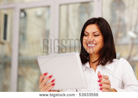 Laughting businesswoman holding tablet computer and looking at it