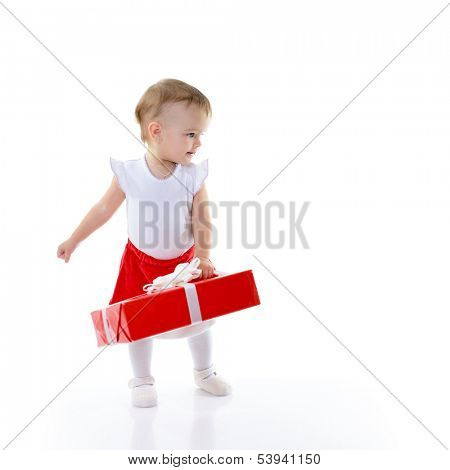 Holidays, baby girl holding a present and looking rigth at copyspace, christmas, birthday, new year, x-mas concept - happy child girl with gift boxes 