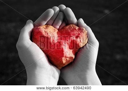 Stone shining red heart in hand