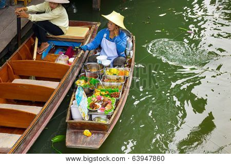 RATCHABURI, THAILAND - MARCH 24: Local peoples sell fruits, food and souvenirs at famous tourist attraction Damnoen Saduak floating market on March 24, 2014 in Ratchaburi, Thailand.