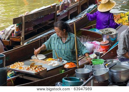 RATCHABURI, THAILAND - MARCH 24: Local peoples sell fruits, food and souvenirs at famous tourist attraction Damnoen Saduak floating market on March 24, 2014 in Ratchaburi, Thailand.