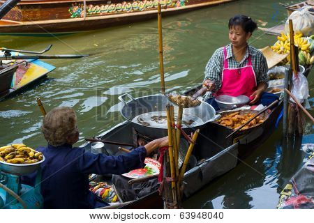 RATCHABURI, THAILAND - MARCH 24: Local peoples sell fruits, food and souvenirs at famous tourist attraction Damnoen Saduak floating market on March 24, 2014 in Ratchaburi, Thailand.