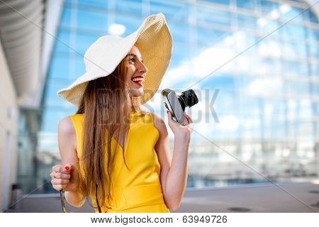 Young Traveling Woman With Photo Camera And Panama Dressed In Yellow Dress Standing In Front Of The