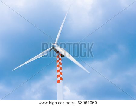 Wind Turbine In Movement Under Blue Sky And Clouds