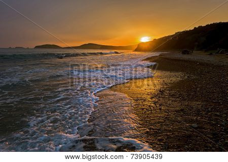 waves on the beach against sunset of russian isle Putyatin 