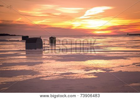 Ice fishing at sunset along the shores of rural Prince Edward Island.