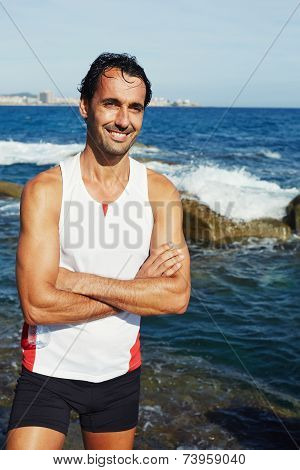 Fit male jogger standing on seaside while resting after run