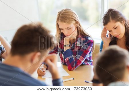 education, school, test and people concept - group of students with papers thinking or making test