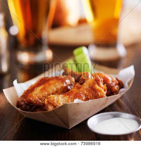 buffalo chicken wings in disposable tray with celery, ranch, and beer